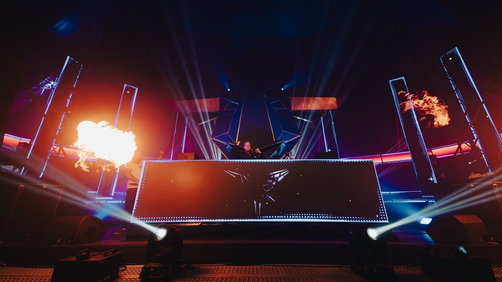 Een DJ booth op een festival met een LED scherm erop. Dit brengt een unieke sfeer op de overdekte stage.