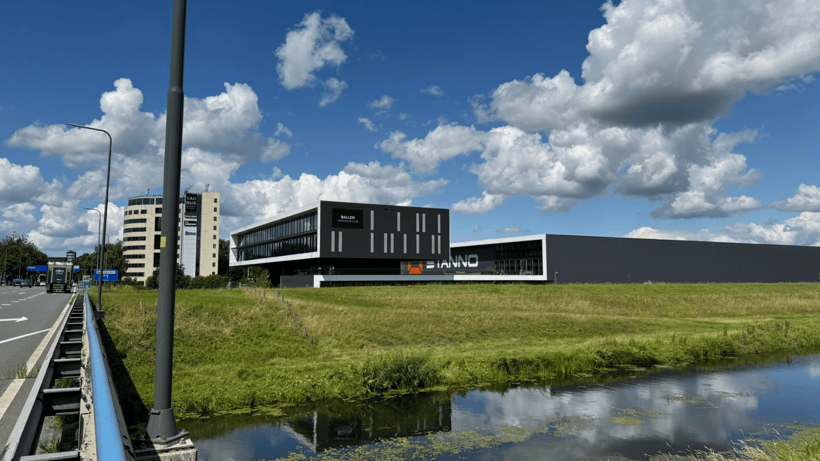 Dit is een prachtig project om de high-end zakelijke markt aan te spreken. Bij Deventrade (bekend van merken als Stanno en Hummel) zien we een strakke integratie van een LED-display in de architectuur van een modern bedrijfspand. Hier gaan we focussen op termen als gevelreclame, outdoor LED wall, en corporate branding. Foto-optimalisaties (Deventrade / Stanno) 1. Het totaaloverzicht (Links: Pand aan het water) Bestandsnaam: outdoor-led-gevelreclame-deventrade-stanno.jpg Alt-tekst: Groot outdoor LED-scherm geïntegreerd in de moderne architectuur van het Deventrade bedrijfspand langs de snelweg