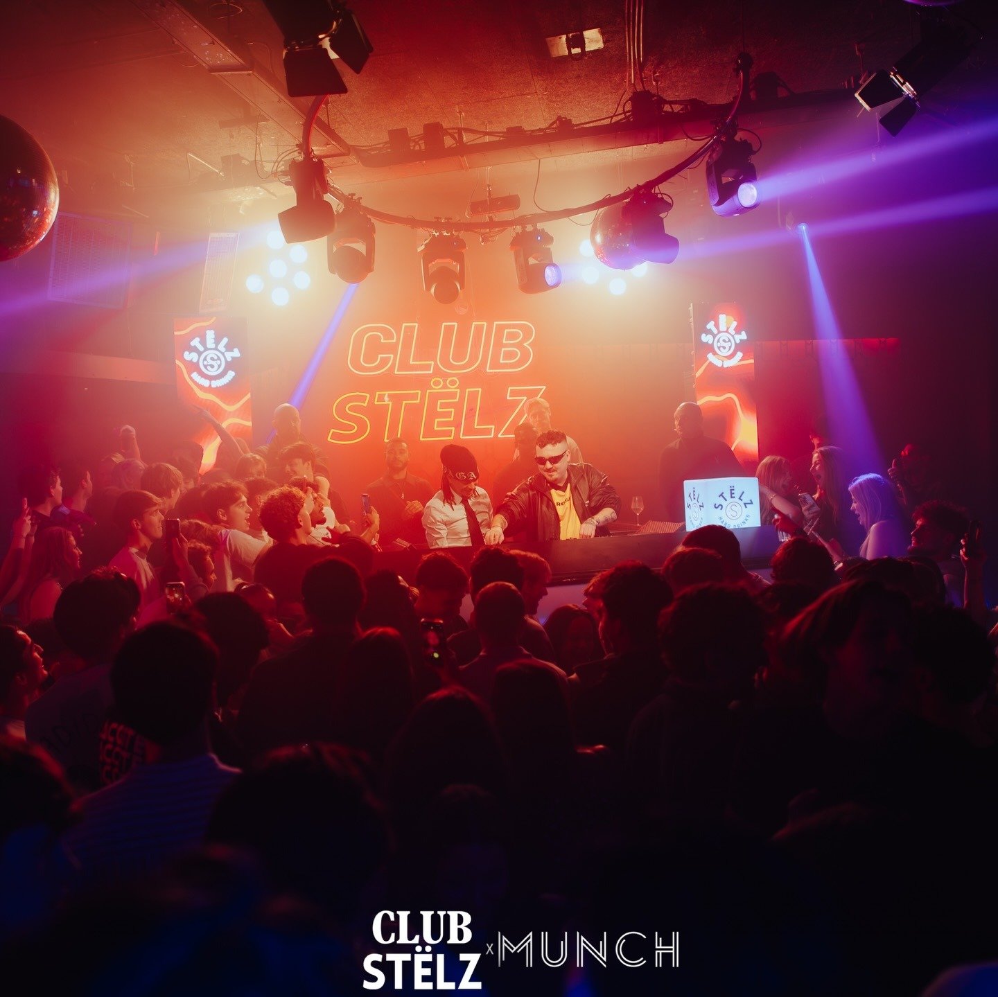 Sfeervolle overzichtsfoto van een drukke nachtclub tijdens een evenement. Een DJ draait muziek achter een booth met een verlicht Stëlz-logo, terwijl een grote groep feestgangers danst en filmt met hun telefoons. Op de achtergrond schijnt een grote neontekst 'CLUB STËLZ' in rood licht, omringd door felle clublampen. Onderaan staat het logo 'CLUB STËLZ x MUNCH'.