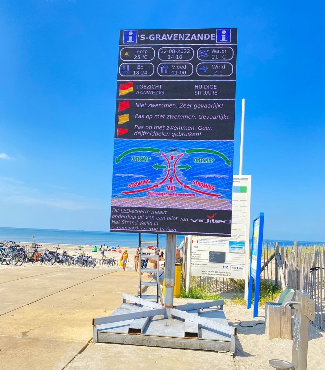 Mobiel LED-informatiescherm van Vidiled op het strand van 's-Gravenzande, tonend de actuele vlagstatus en veiligheidsinstructies.
