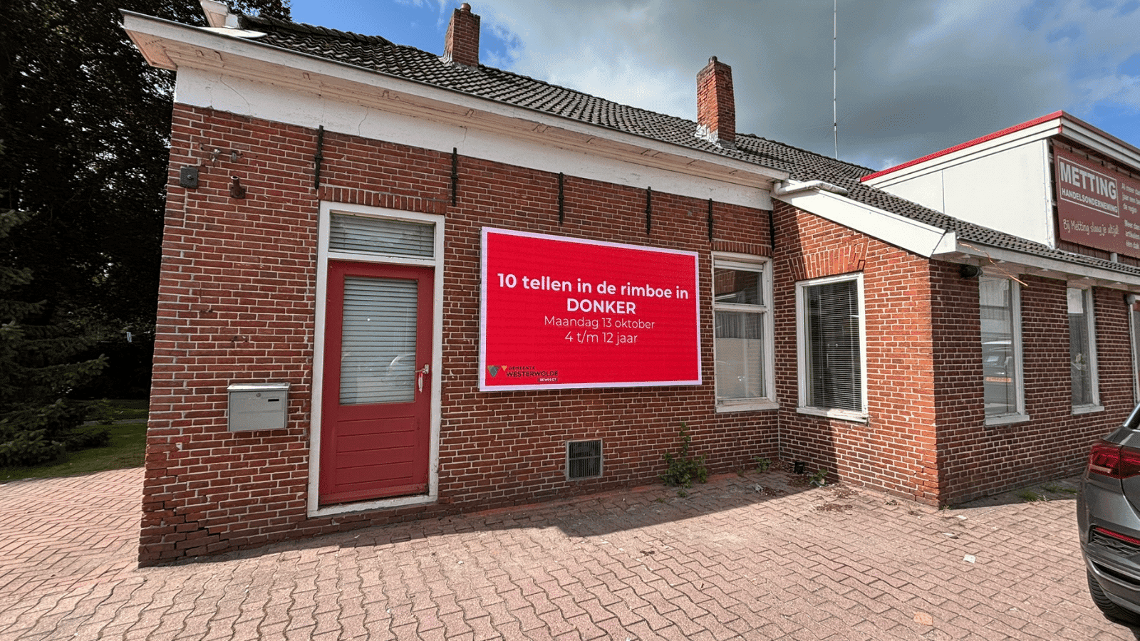 Close-up van het Vidiled digitale informatiebord in Bellingwolde met een rode achtergrond en witte tekst over sportevenementen