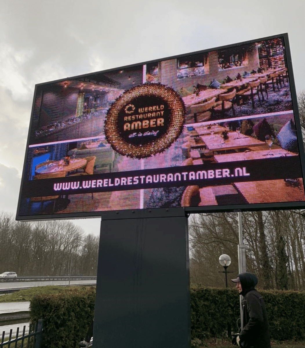 Close-up van het Vidiled digitale informatiebord bij Wereldrestaurant Amber in Waspik met het logo en de website prominent in beeld