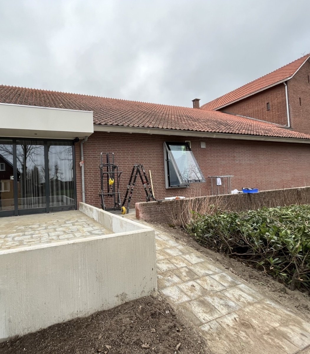 Zijaanzicht van een slank outdoor LCD scherm aan een bakstenen gevel, geleverd door Vidiled voor Gemeente Biezenmortel.