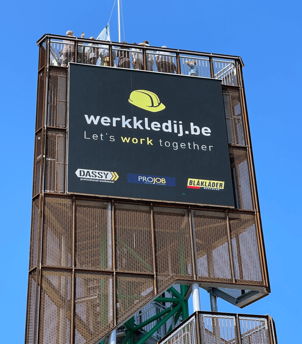 Vidiled LED-reclamebord op de Mariatoren Hapert met advertentie van werkkledij.be, groot formaat buitenscherm tegen blauwe lucht