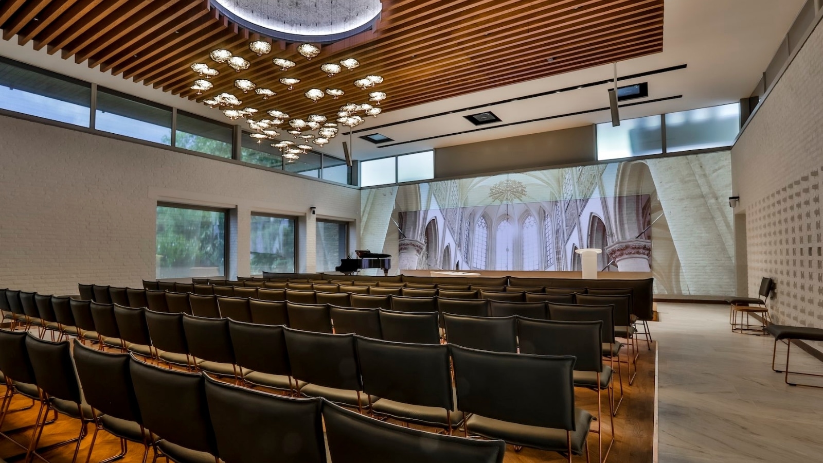Overzicht van de aula bij Zuylen Uitvaartverzorging Breda met het Vidiled LED-display geïntegreerd in de moderne zaal met design verlichting