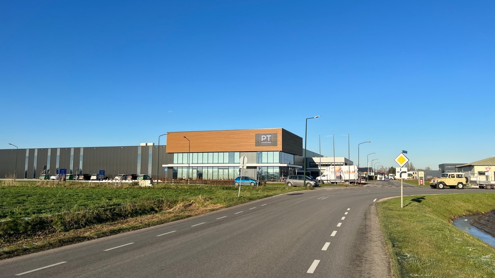 Totaaloverzicht van PT Creations bedrijfspand langs de N267 met Vidiled LED-gevelscherm goed zichtbaar voor passerende automobilisten
