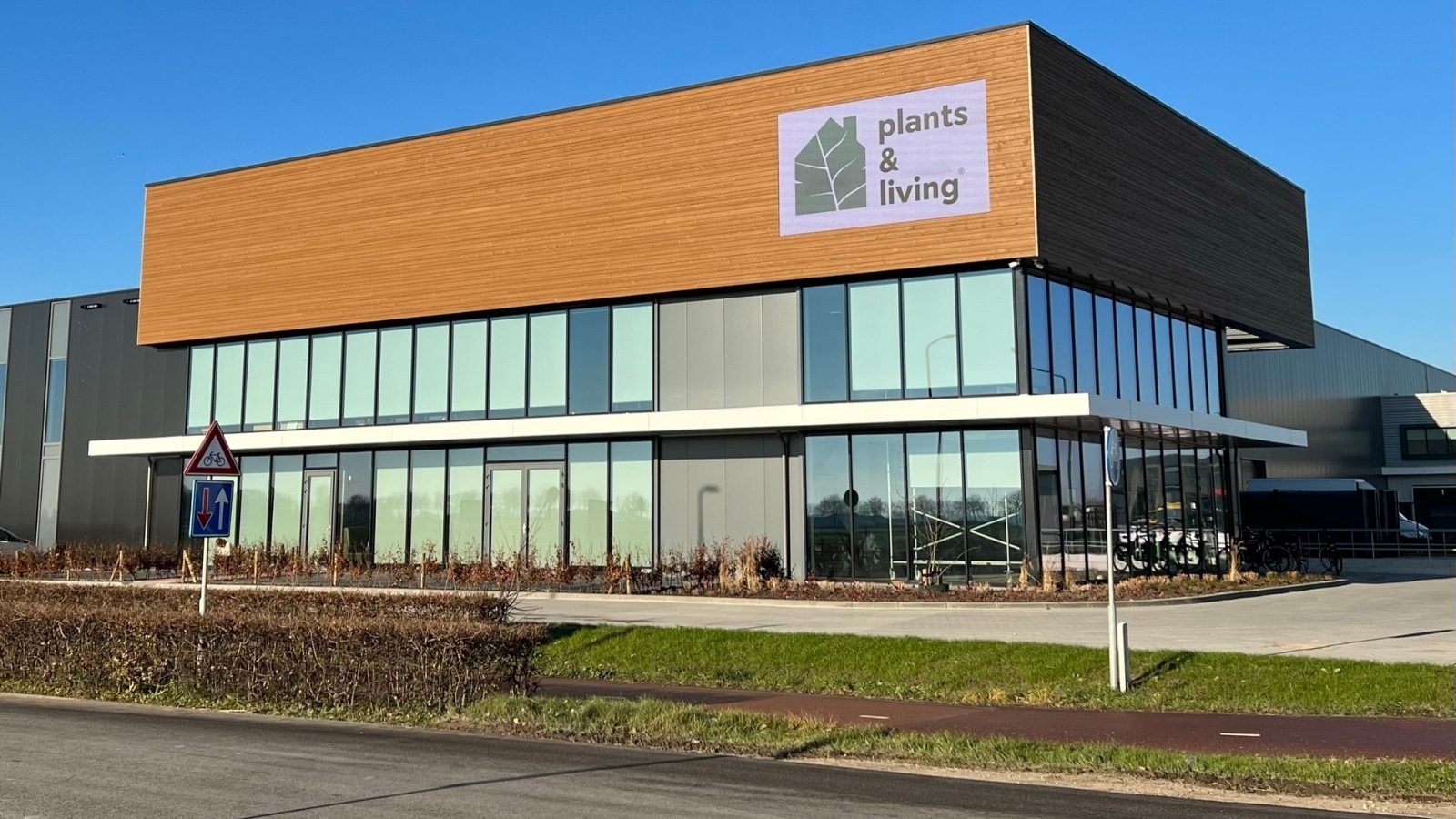 Vidiled LED-gevelscherm op bedrijfspand PT Creations met advertentie van Plants & Living, modern kantoorgebouw met houtlook gevel