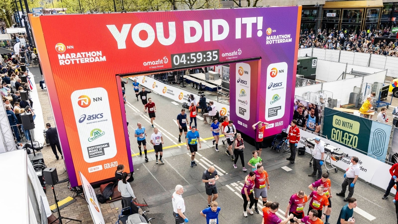 Vidiled LED-scherm met YOU DID IT-boodschap langs het parcours van de NN Marathon Rotterdam met massa hardlopers op de voorgrond