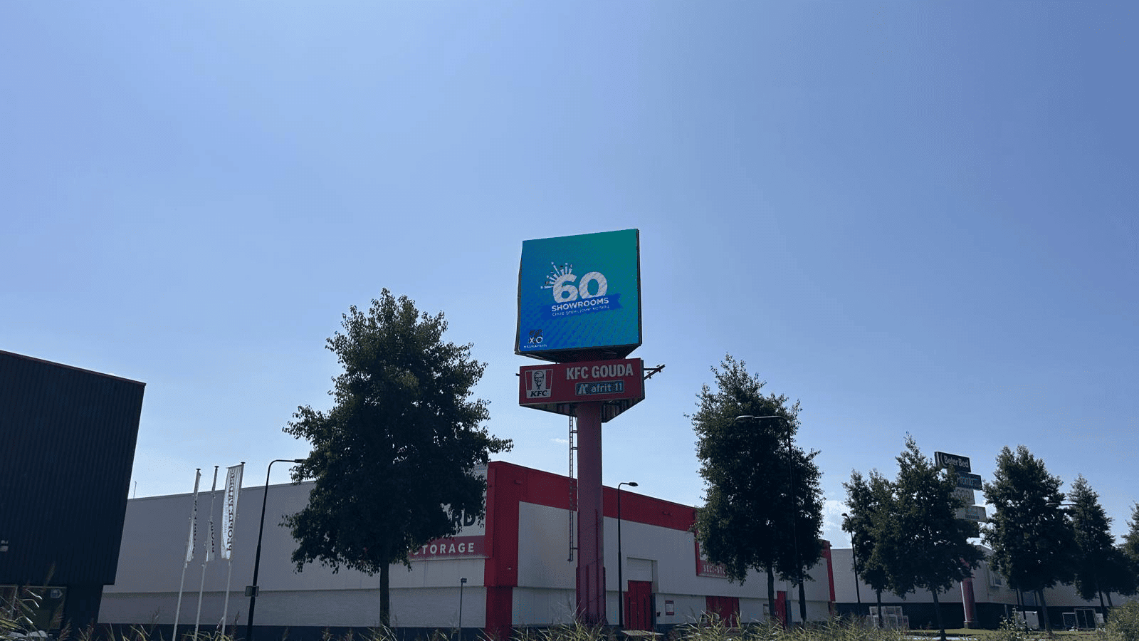Totaaloverzicht van het retailpark in Gouda met de Vidiled LED-mast die boven de gebouwen uitsteekt voor maximale zichtbaarheid