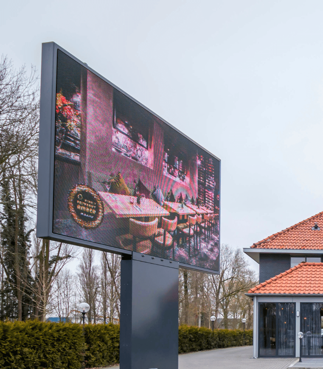 Vrijstaande Vidiled LED-mast langs de weg bij Wereldrestaurant Amber in Waspik met een sfeervolle advertentie van het restaurantinterieur
