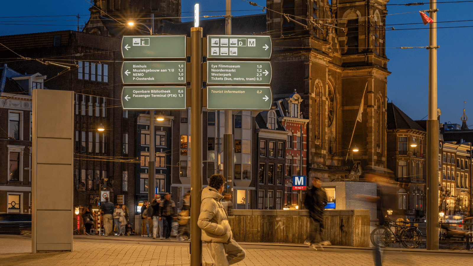 Gedetailleerde weergave van verlichte multidirectionele mast, die de weg wijzen naar hotspots in Amsterdam in de avond.