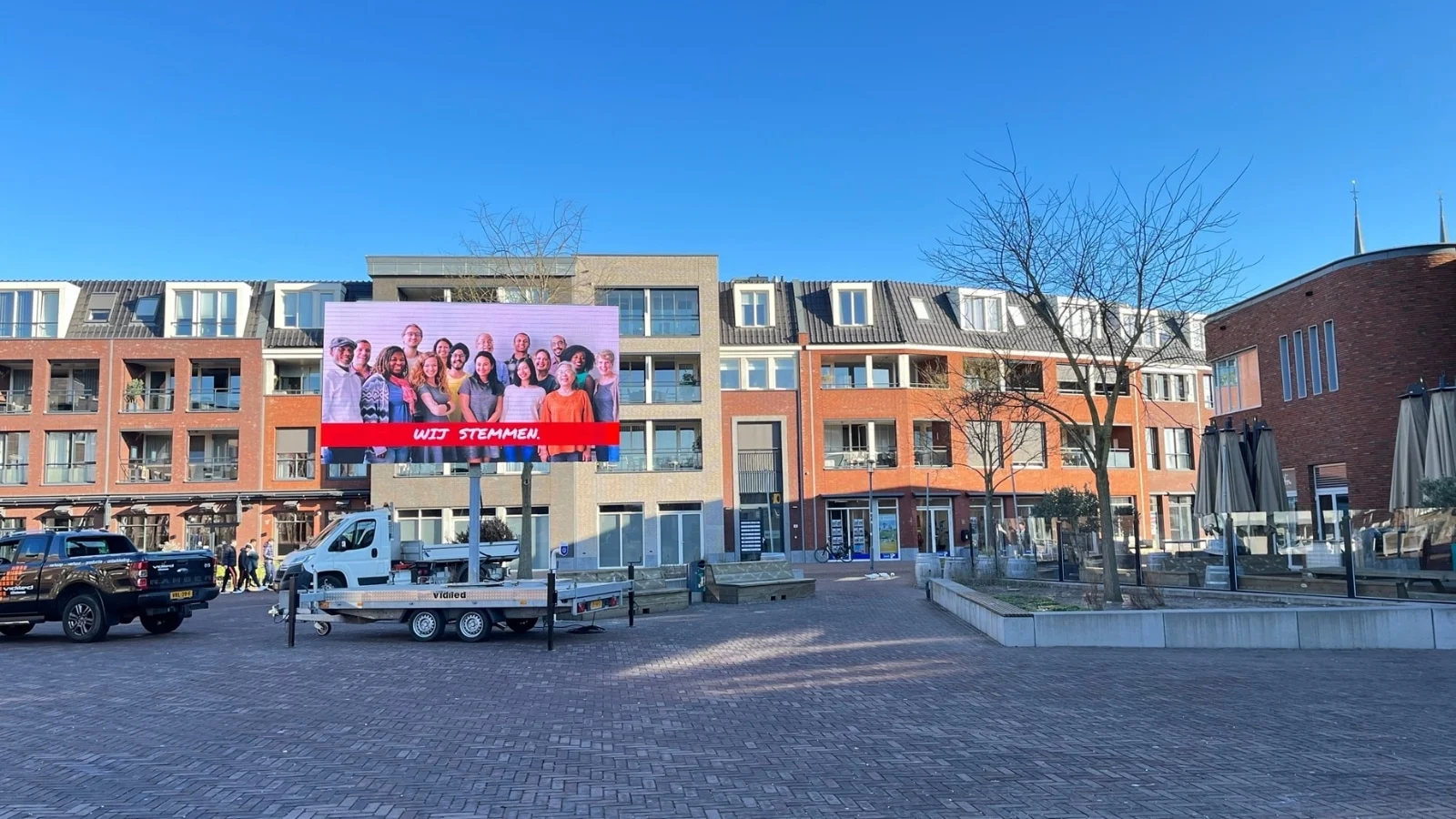 Grootformaat digitaal reclamebord op aanhanger van Vidiled met heldere weergave van verkiezingsposters.